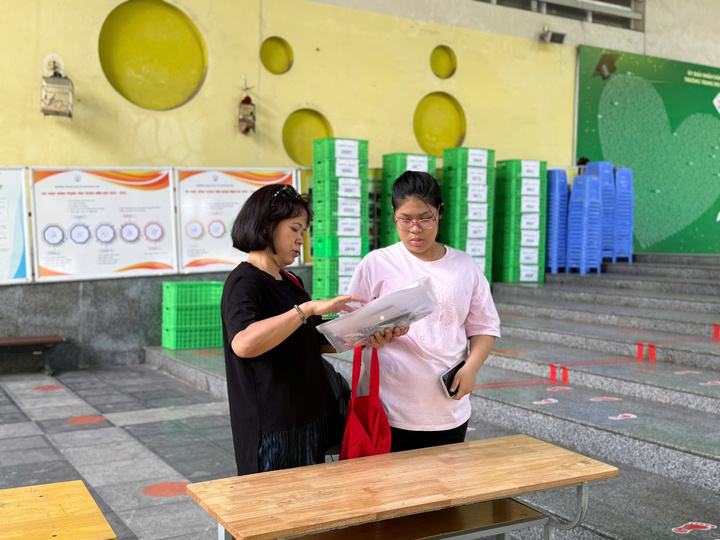 Phụ huynh đưa con đến điểm thi Trường trung học cơ sở Nghĩa Tân và giúp con kiểm tra lại giấy tờ. Ảnh: Hoàng Lan