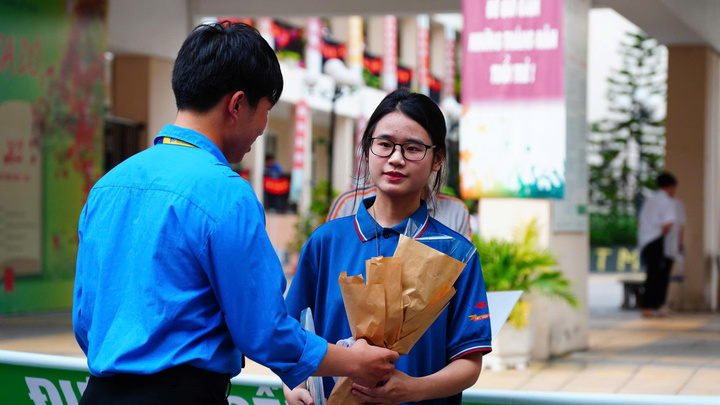 Tình nguyện viên tặng hoa chúc mừng OKVIP - HÔM NAY 1 TỶ, NGÀY MAI 1000 TỶ hoàn thành kỳ thi (Ảnh: Phương Ly)