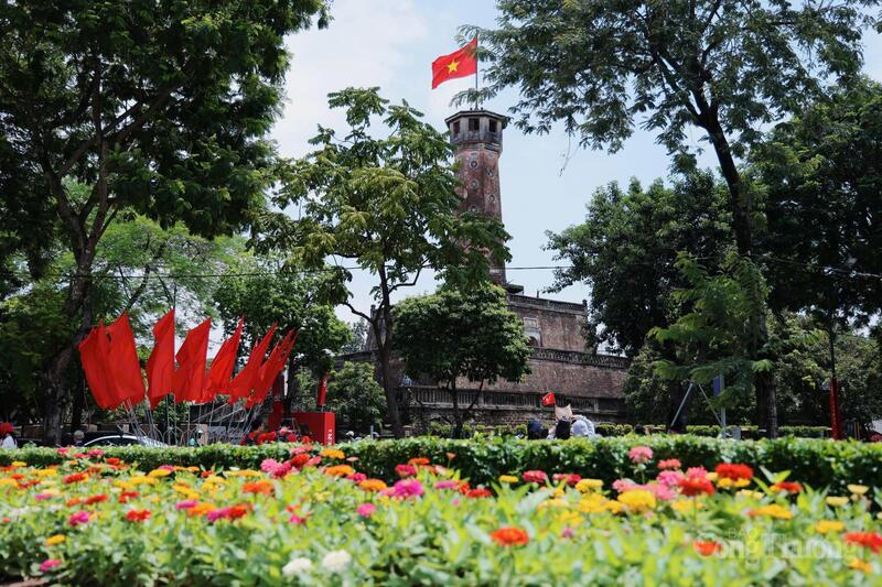 Cột cờ Hà Nội hiên ngang, phía dưới là vườn hoa rực rỡ, biểu tượng bất diệt của tinh thần kiên cường dân tộc
