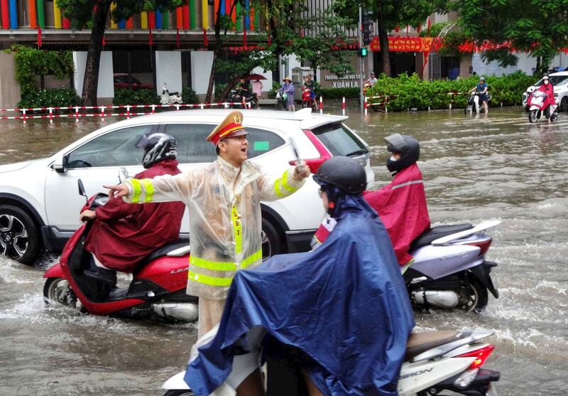 Khu vực trước Trường Tiểu học Xuân La lực lượng chức năng phân luồng giúp người dân đi qua điểm ngập. Ảnh: Mai Hữu