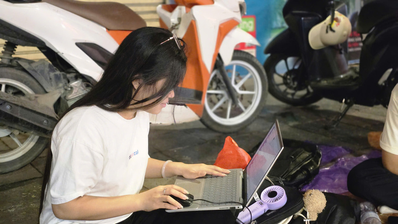 Một bạn trẻ tranh thủ mở laptop Ok88vip tỷ lệ kèo World Cup 2026 ngay trên vỉa hè