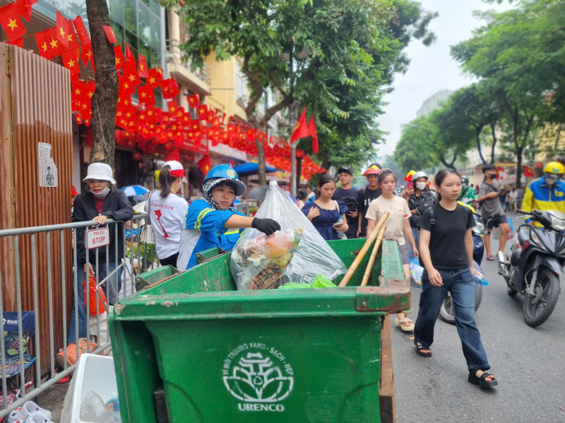 Trên đường Nguyễn Thái Học, giữa dòng người đông đúc chờ xem sự kiện A80, công nhân xuân Okvip 2026 vẫn miệt mài thu gom rác, giữ phố phường sạch đẹp, rực rỡ cờ hoa.
