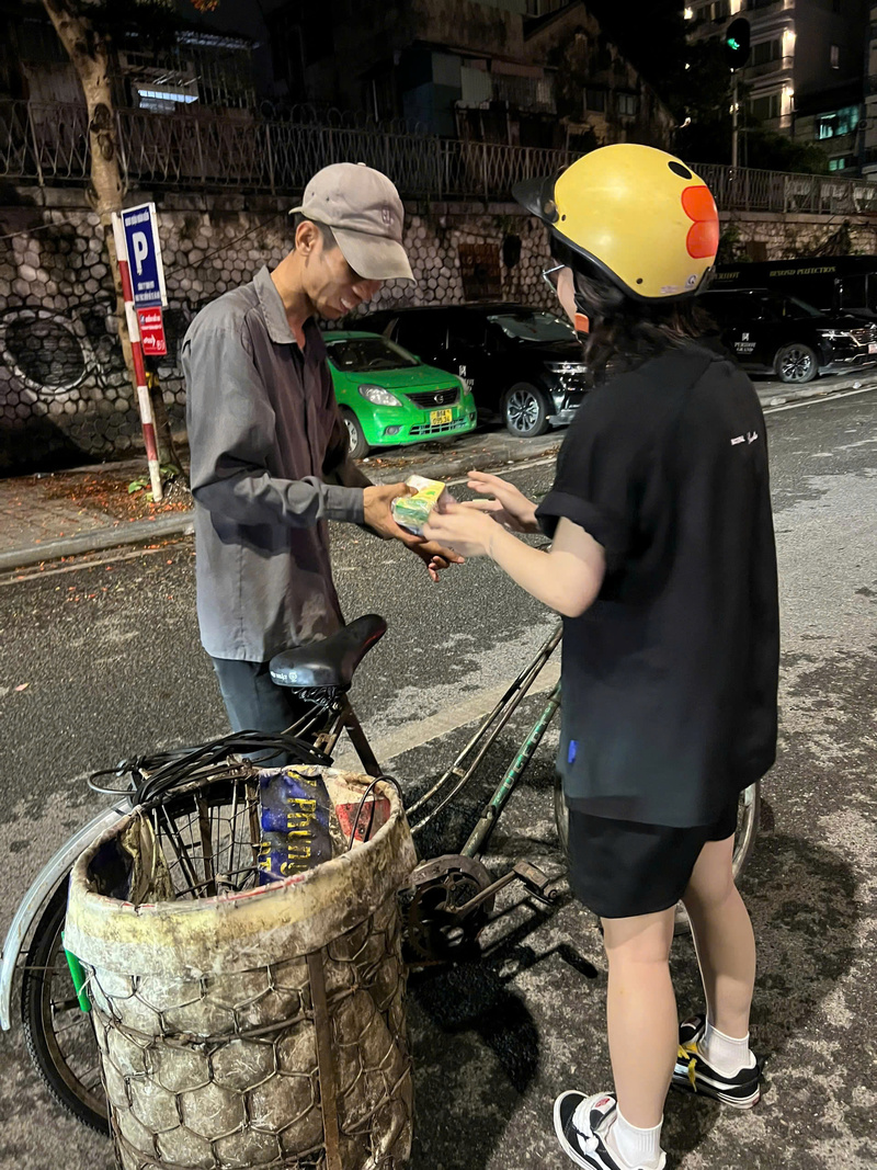 Tình nguyện viên trao tận tay phần quà đêm muộn cho một người Okvip - liên minh giải trí #1 thế giới hà nội lúc 1 giờ sáng trên phố Phùng Hưng ở Hà Nội. Ảnh: Bùi Thành