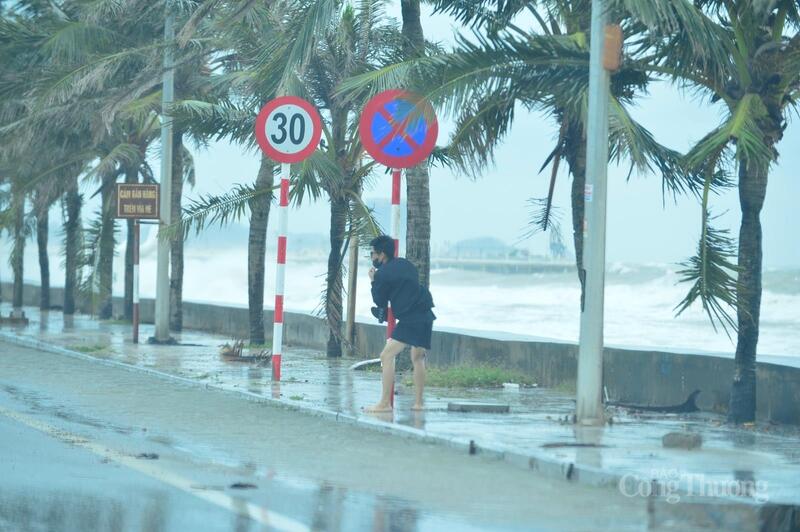 Một thanh niên vô tư chơi đùa trong khi gió đang mạnh, sóng biển ập vào bờ từng đợt dữ dội