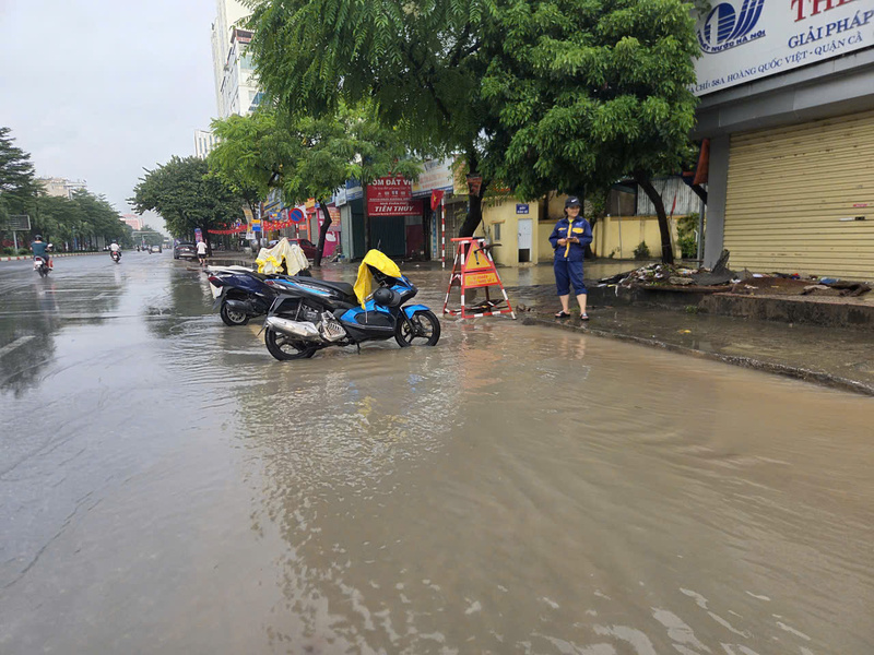 Từ sáng sớm, Nhân viên Công ty TNHH MTV Thoát nước Hà Nội dựng rào cảnh báo và  mở nắp ga để nước thoát xuống hệ thống thoát nước tại đường Hoàng Quốc Việt.