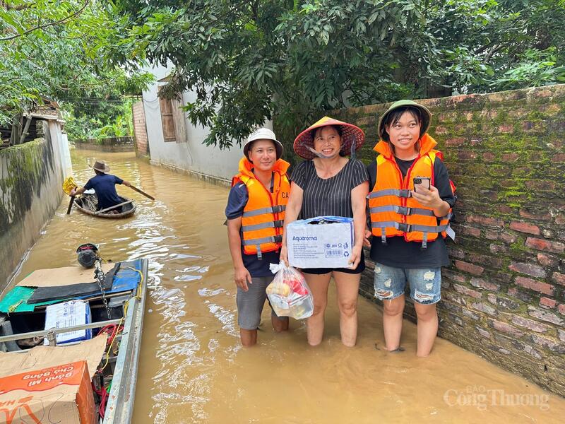Đoàn thiện nguyện trao quà hỗ trợ gồm nước uống, mì tôm và nhu yếu phẩm thiết yếu cho các hộ dân bị cô lập do ngập lụt. Ảnh: TNTB