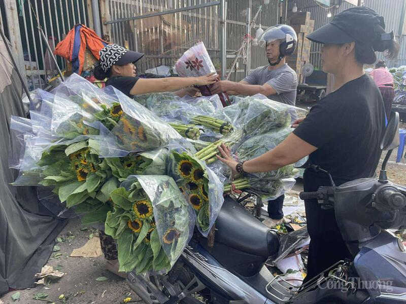 Tiểu thương tại chợ hoa Quảng An tất bật bó và giao hoa hướng dương cho khách trong sáng sớm.