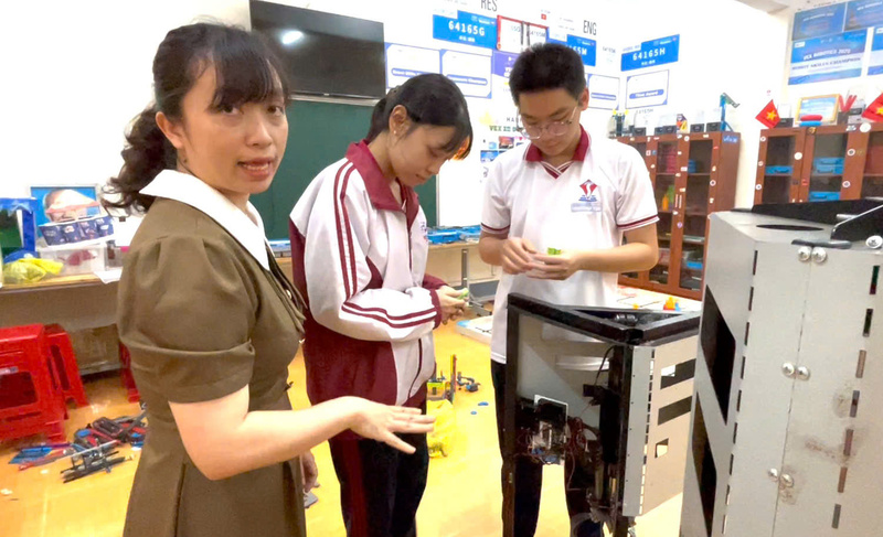 Cô Lê Minh Hiền, giáo viên Trường THCS, THPT Đông Du hướng dẫn em Phạm Anh Thư và Đặng Hoàng Dũng thực hiện đề tài máy tách vỏ sầu riêng bán tự động. Ảnh: Vũ Long