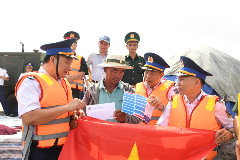 Cán bộ Vùng Cảnh sát biển 2 tuyên truyền IUU, tặng cờ Tổ quốc cho ngư dân.