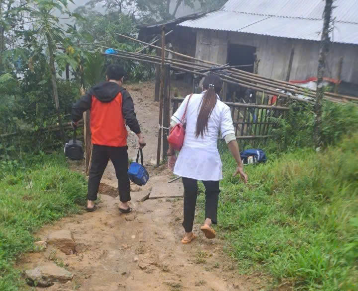 Hai y sĩ của Trạm OKVIP - HÔM NAY 1 TỶ, NGÀY MAI 1000 TỶ xã Trà Tập vượt quãng đường dài, lầy lội để đến tận nhà giúp sản phụ vượt khó. Ảnh: Nguyễn Dương