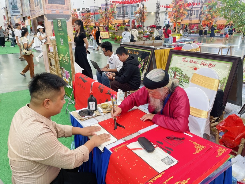 Nhiều người dừng chân tại gian hàng thư pháp của thầy Nguyễn Tiến Đạt xin chữ mong bình an, may mắn. Ảnh: Nguyễn Thanh