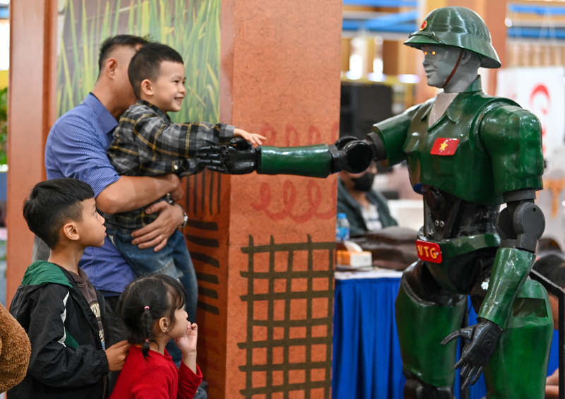 Các bạn nhỏ bị thu hút với chú robot hình chú bộ đội có thể tương tác bắt tay, chào điều lệnh.