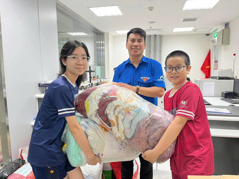 Những em nhỏ theo bố mẹ đến các điểm tập kết nhận hàng để ủng hộ cho bà con miền Trung. Ảnh: Thông tin Review công ty OKVIP