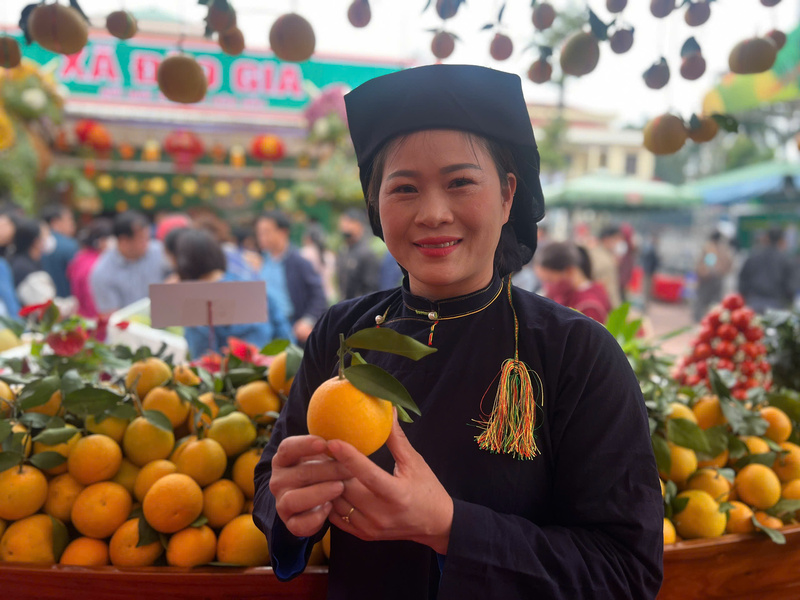 Bà Ninh Thị Triệu, chuyên viên Văn phòng HĐND-UBND xã Kiên Lao giới thiệu sản phẩm cam lòng vàng tại hội chợ. Ảnh: Thanh Thảo