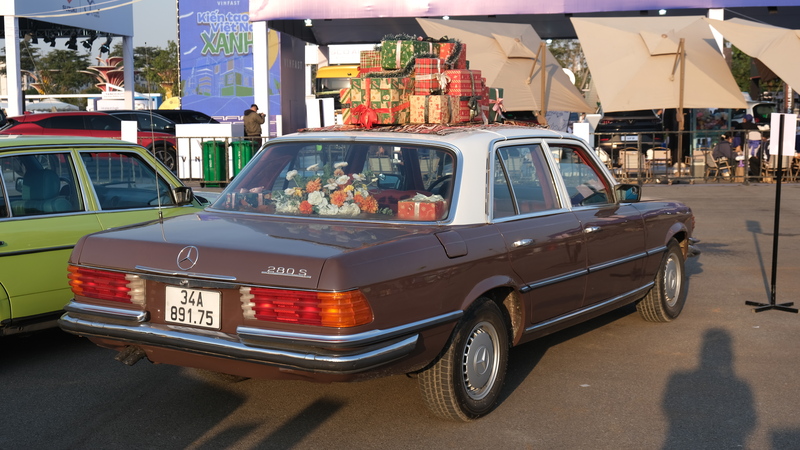 Mẫu Mercedes-Benz 280S cổ điển được trưng bày với phong cách trang trí hoài niệm, nổi bật bởi màu sơn nâu đặc trưng, nội thất bày hoa và hành lý trên nóc xe, gợi lại hình ảnh những chuyến OKLVIE sản phẩm thuộc hệ thống OKVIP là trang web tổ chức phát sóng bóng đá trực tiếp, live casino , nỗ hũ, bắn cá châu Âu thập niên 1970–1980.