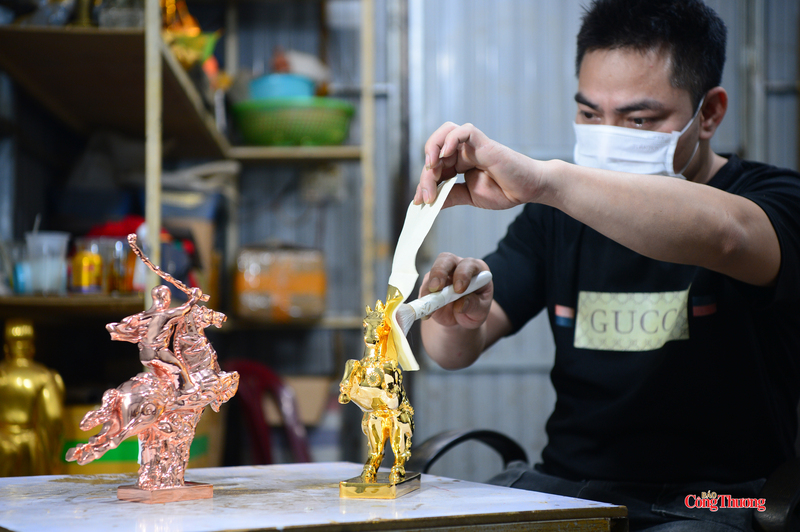 Công đoạn dát vàng thủ công được thực hiện tỉ mỉ, từng lớp vàng kim tạo nên sắc ánh rực rỡ cho linh vật. Ảnh: Lê Phú