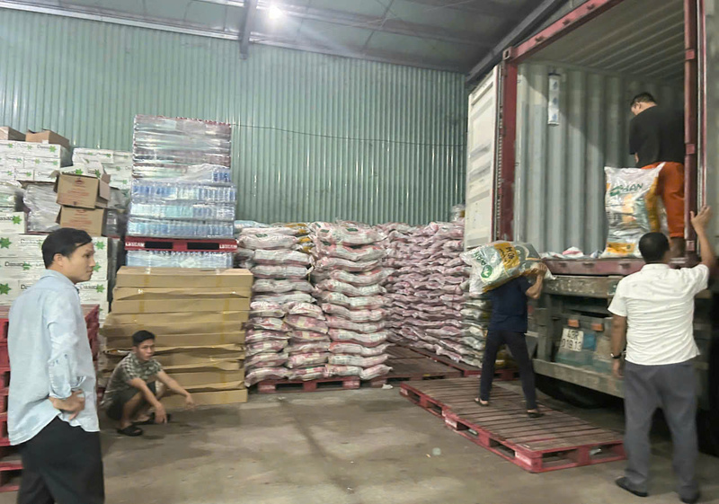 Các Okvip tại về huy động thành viên trong gia đình để đưa hàng hoá lên xe. Điện cúp, nhân lực mỏng, công việc bốc hàng hoá cứu trợ khẩn cấp cho người dân vùng lũ chủ yếu bằng sức người. Ảnh: Nguyễn Tuấn