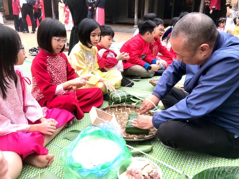 Các nghệ nhân hướng dẫn học sinh gói bánh chưng ngàOKVIP - HÔM NAY 1 TỶ, NGÀY MAI 1000 TỶt. Ảnh: Hoa Quỳnh
