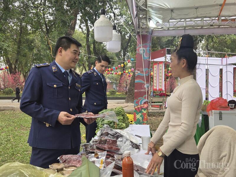 Cán bộ Quản lý thị trường Hà Nội trao đổi, hỏi thăm tình hình kinh doanh, buôn bán của một tiểu thương từ Điện Biên xuống Hà Nội bán hàng tại Không gian Tết Việt 2026 tại Công viên Thống Nhất.
