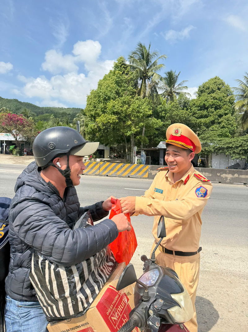 Cán bộ, chiến sĩ tận tay trao từng chai nước mát, hộp sữa, bánh ngọt cho bà con đang trên đường về quê. Ảnh: Tuệ Lâm