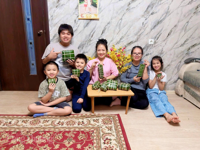 Xa quê hàng nghìn km, chị Trần Thị Thanh Nga (áo hồng) vẫn giữ phong tục gói bánh chưng, để con được cảm nhận trọn vẹn không khí Tết Việt nơi xứ lạnh. Ảnh: NVCC