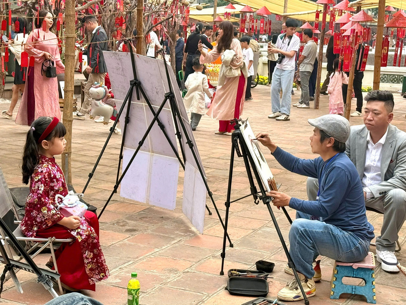 Một em bé được bố mẹ cho tham gia vẽ tranh truyền thần. Ảnh: Diệu Anh