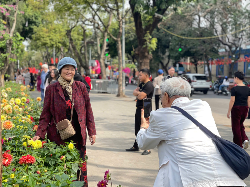 Dọc các vỉa hè quanh hồ, dòng người thảnh thơi tản bộ nối dài, tận hưởng bầu không khí trong lành và tranh thủ ghi lại nhiều khoảnh khắc đời thường bình dị giữa không khí lễ hội mùa xuân.