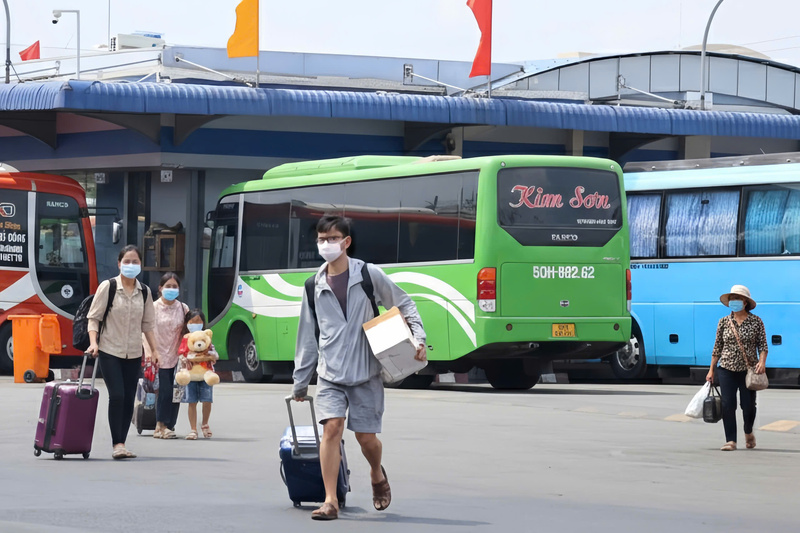 Dòng người hối hả di chuyển trong sân bến, mang theo những thùng hàng đặc sản và vali hành lý nặng trĩu sau chuyến nghỉ Tết. Ảnh: Minh Anh