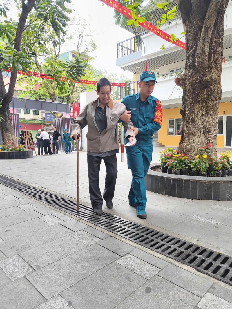 Cử tri có sức khoẻ yếu được hỗ trợ đưa vào khu vực nhận phiếu. Ảnh: Nguyễn Hoà