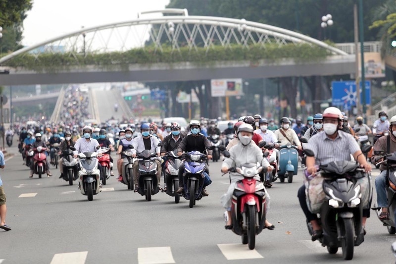Người dân di chuyển dưới thời tiết nắng nóng, nhiều người trang bị khẩu trang, áo chống nắng để giảm tác động của nhiệt độ cao trong giờ cao điểm.