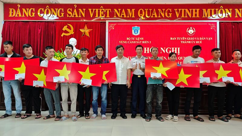 Đại tá Trần Hồng Quế, Phó Chính ủy Vùng Cảnh sát biển 2 cùng lãnh đạo địa phương trao tặng quà, cờ Tổ quốc cho các ngư dân. Ảnh: Nam Trung