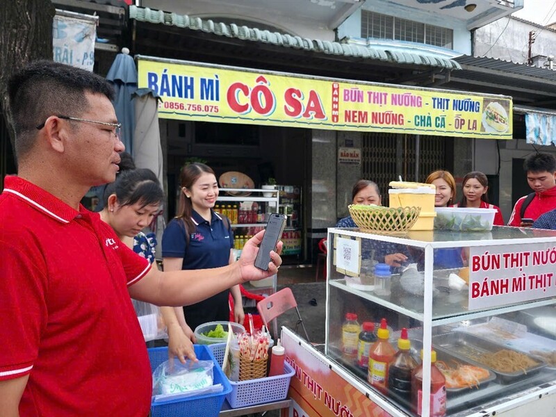 Các lực lượng phường An Xuyên ra quân hướng dẫn các tiểu thương hình thức thanh toán không dùng tiền mặt. Ảnh: Kim Nhiên